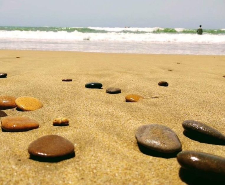 pebbles lying on clean sand and clear water at turtle beach karachi