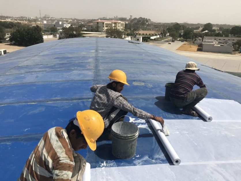 Workers installing insulating sheets on roof