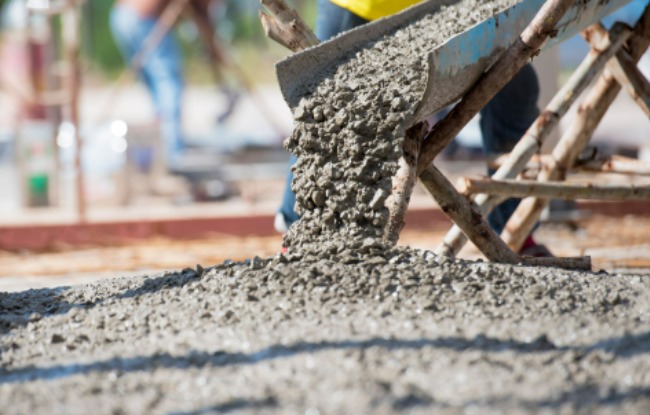 concrete - an artificial construction material flowing out of a wheelie cart onto the ground