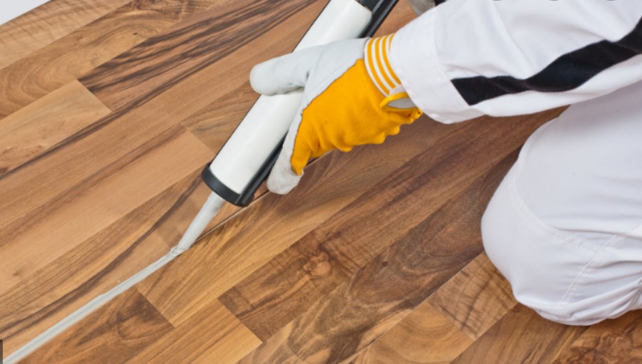 a person sealing the waterproof laminate on the subfloor