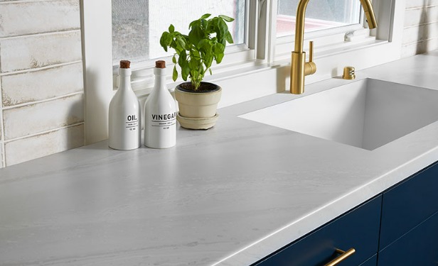 a white kaminate counter with sink and faucet