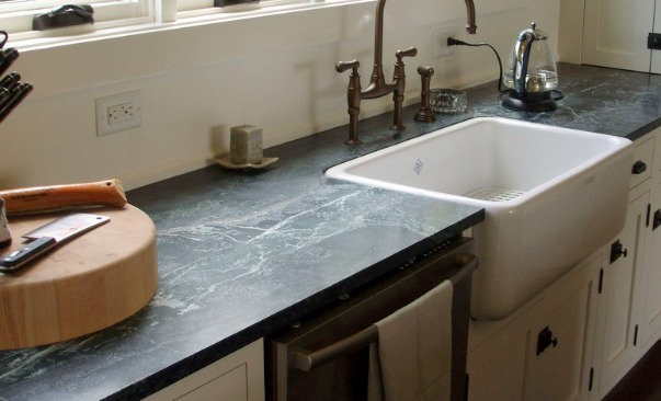 a dark grey soapstone counter with white sink and faucet