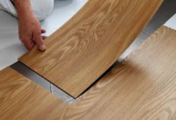 a person installing planks of waterproof sheet on floor 