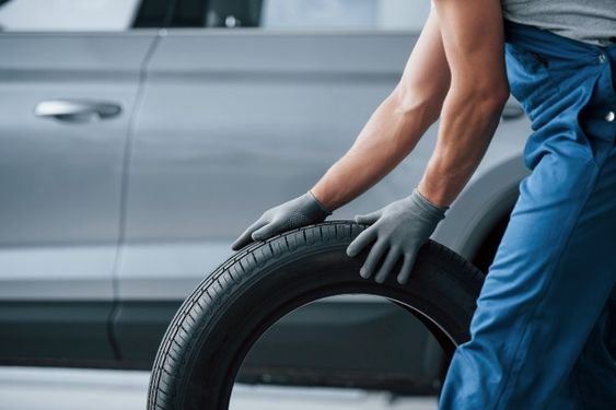 spare tyre being rolled for replacing flat tyre in car