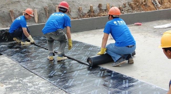 workers applying Bitumen Membrane Waterproofing sheet over the floor