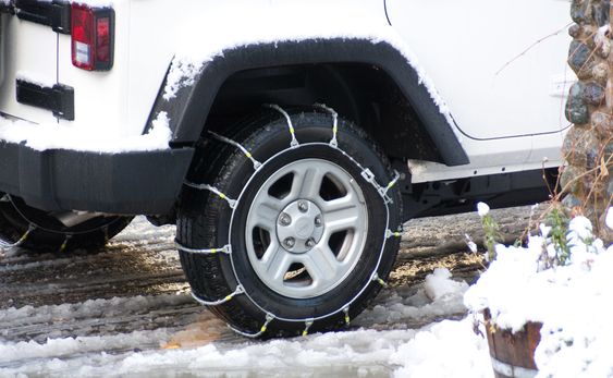snow chains wrapped around tyres in snow