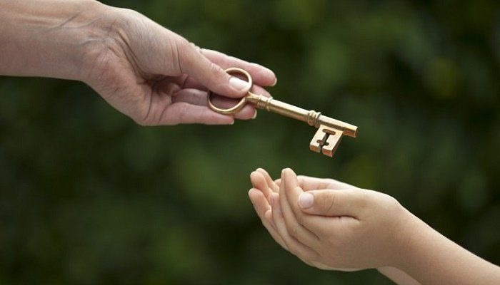A hand places a key in a child's hands