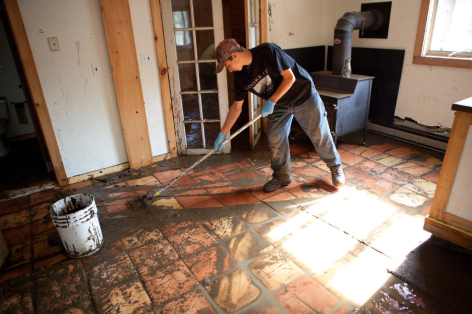 man cleans up mud from flooding caused by tropical storm.