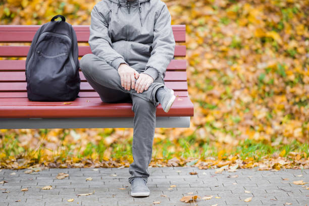 پارک میں بینچ پر بیٹھا ایک شخص اور پاس رکھا ہوا ایک بیگ پیک