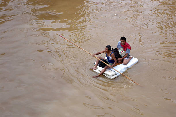 سیلاب میں عارضی کشتی پر بیٹھے دو افراد