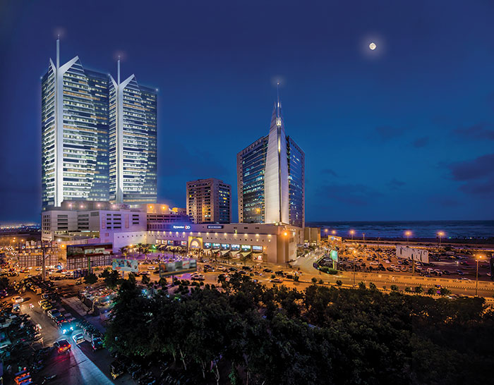 A night view of dolmen tower with hundreds of cars parked in the parking lot