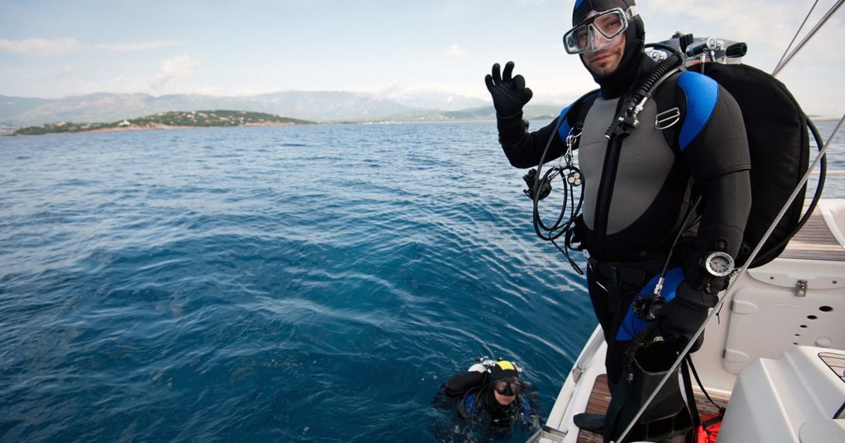 a scuba diver standing on a boat and posing for camera before diving