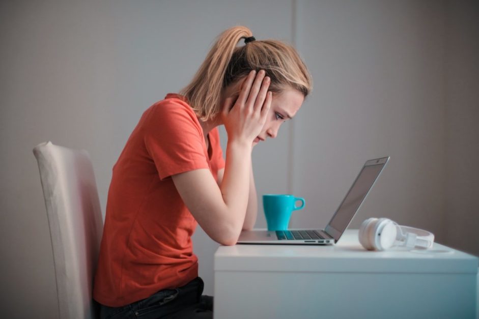 A girl sitting on a chair covering her ears from outcoming noise