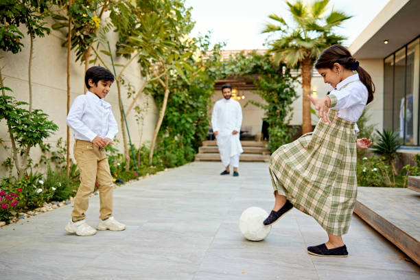 گھر کے صحن میں فٹ بال سے کھیلتے دو بچے