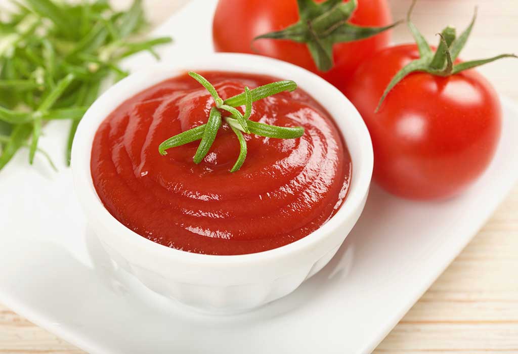 tomato ketchup in a bowl and two tomatoes