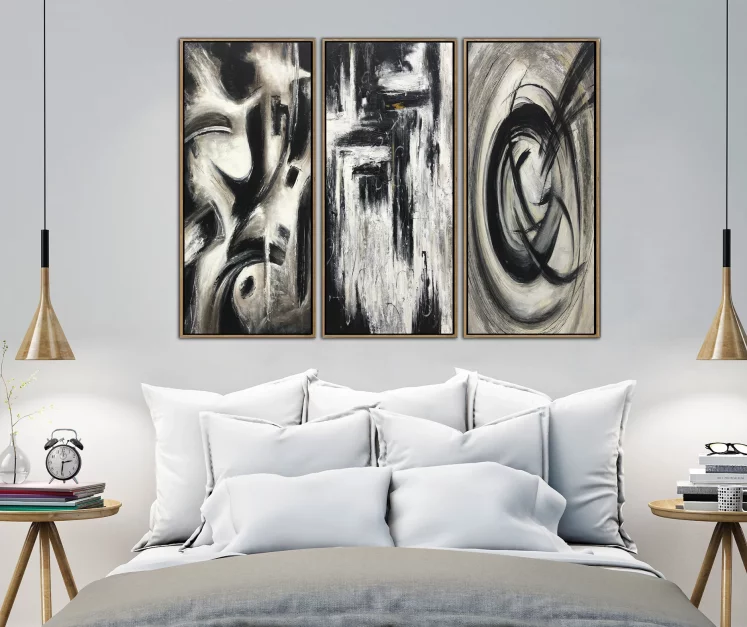 black white and grey paintings above bed