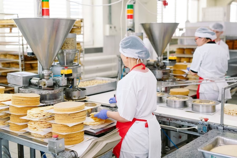 a person decorating cakes in a food factory