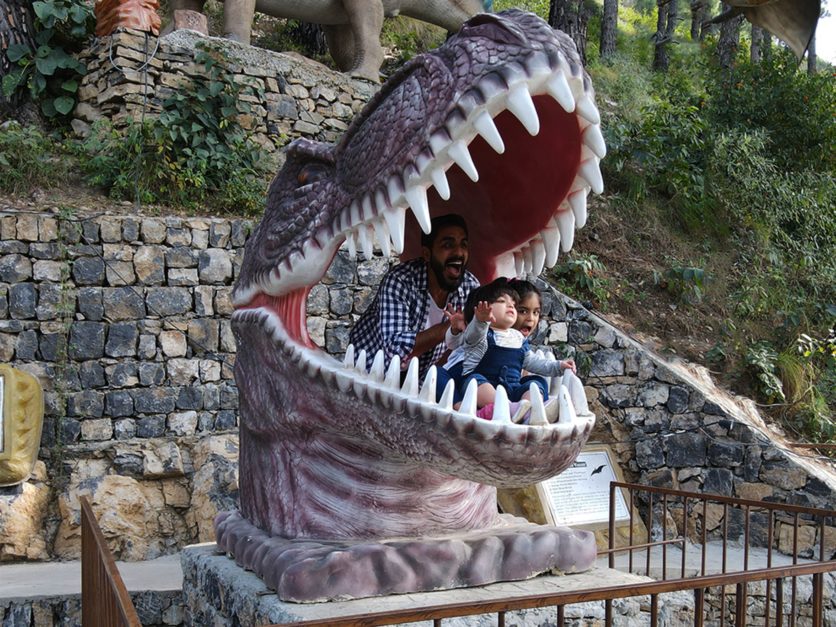 kids sitting inside the statue of dinosaur jaws at the valley