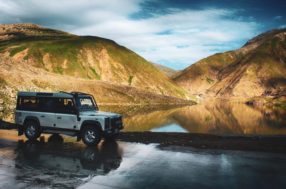 A jeep parked on a road in front of a lake in Astore Valley