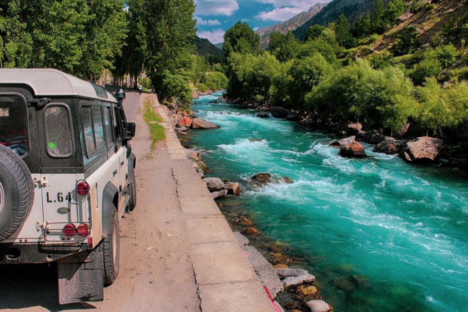 a jeep riding along a river aside