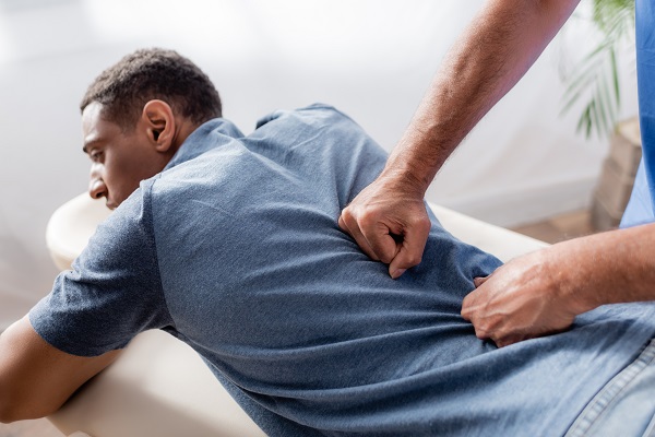 Chiropractor Working With Young And Injured African American Patient