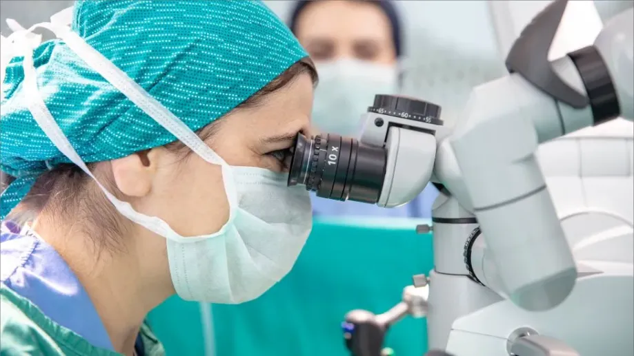 A female neurosurgeon looking into a microscope