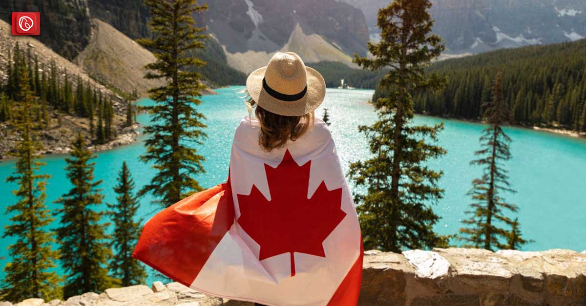 A lady holding a candian flag infront of a lake