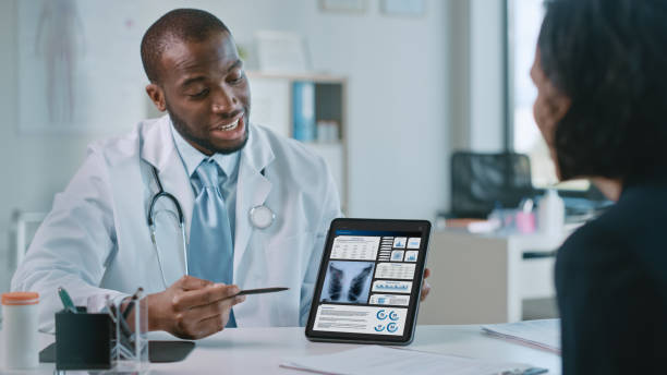 Female Patient Listens to Experienced Pulmonologist Uses Digital Tablet Computer to Show, Explain Lung Analysis Results, Give Advice